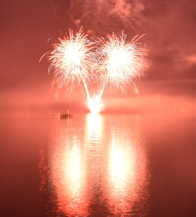 Bright fireworks casting a red reflection across Lake Arbutus.